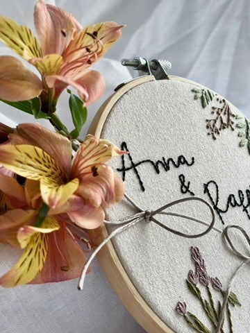 Detalle de porta alianzas bordado a mano en bastidor, tejido de algodón y flores bordadas, ideal para bodas rústicas y boho.