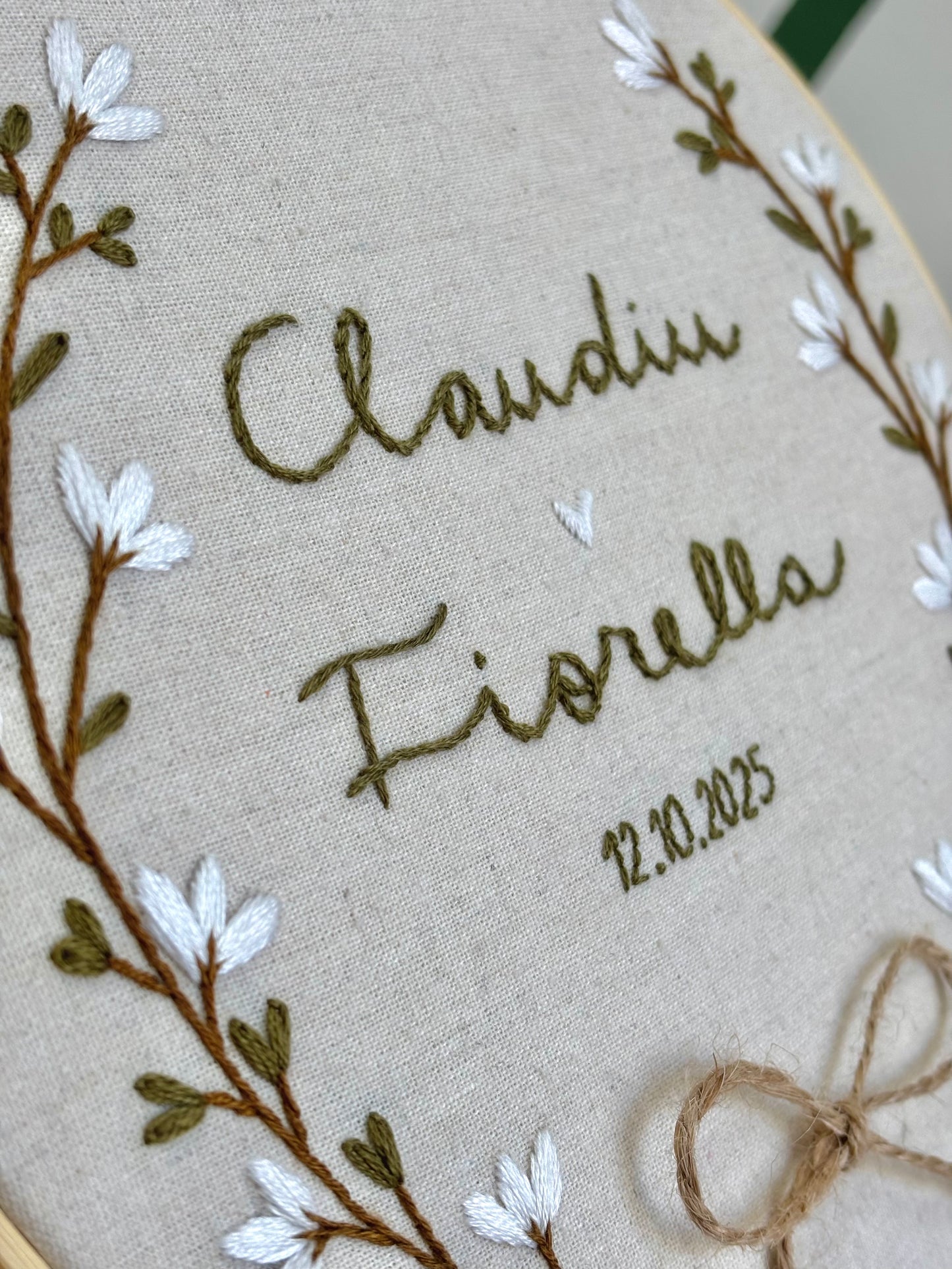 Porta alianzas personalizado con nombres bordados, bastidor de madera y decoración floral hecha a mano sobre algodón natural.
