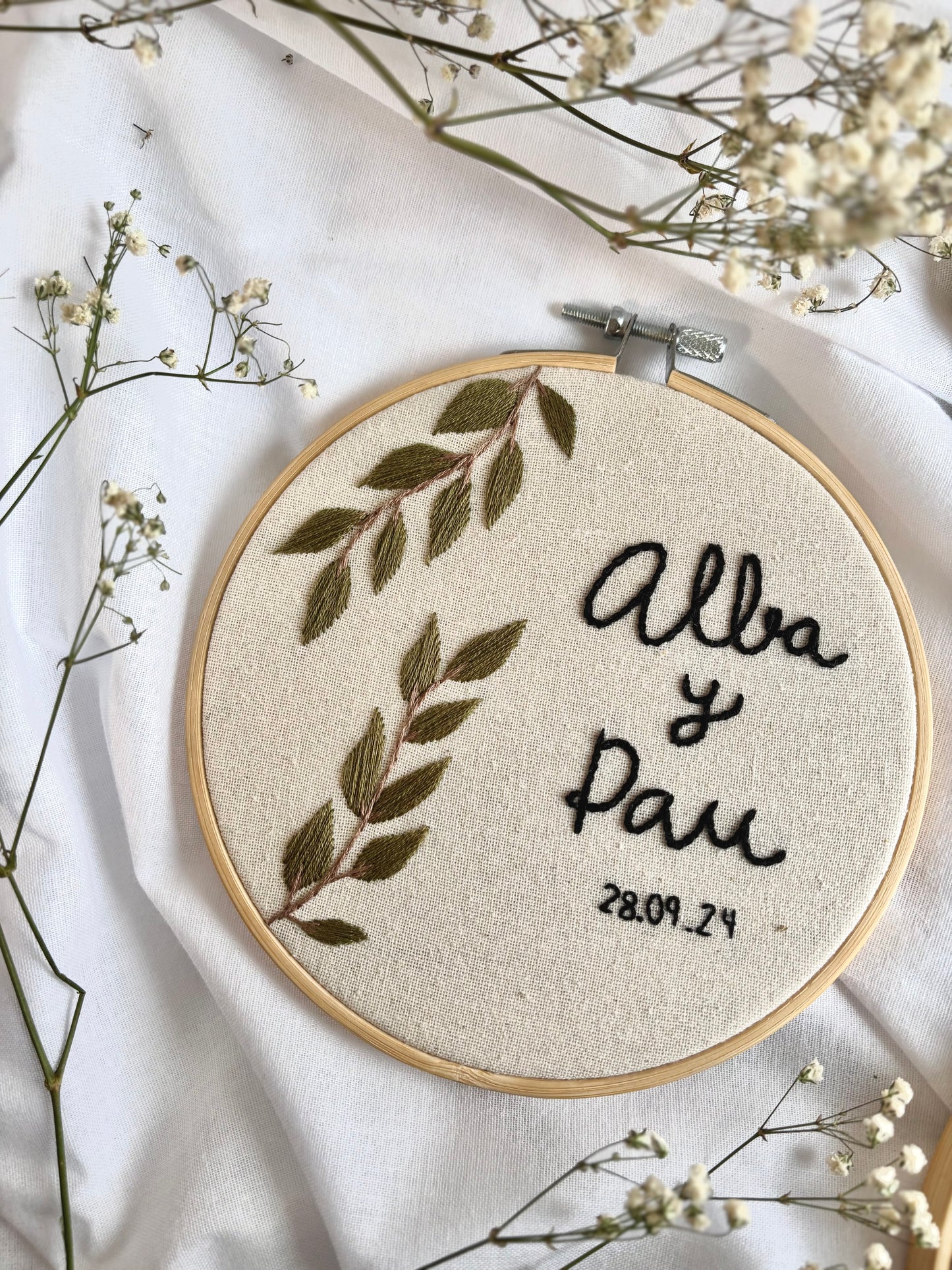 Porta alianzas de boda en bastidor bordado a mano con flores naturales, algodón y estilo rústico elegante.