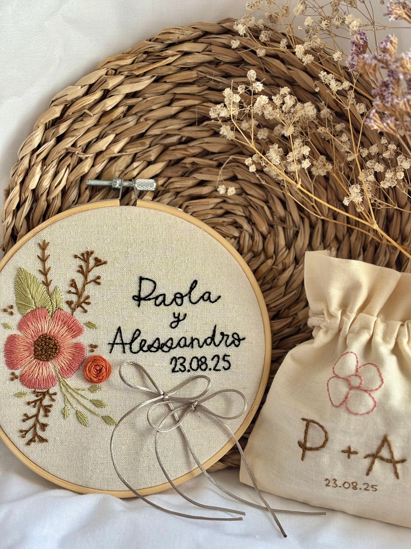 Detalle de boda bordado a mano: pack de porta alianzas y saquito de arras con motivos florales, estilo boho, diseño rústico y personalizado para boda única.