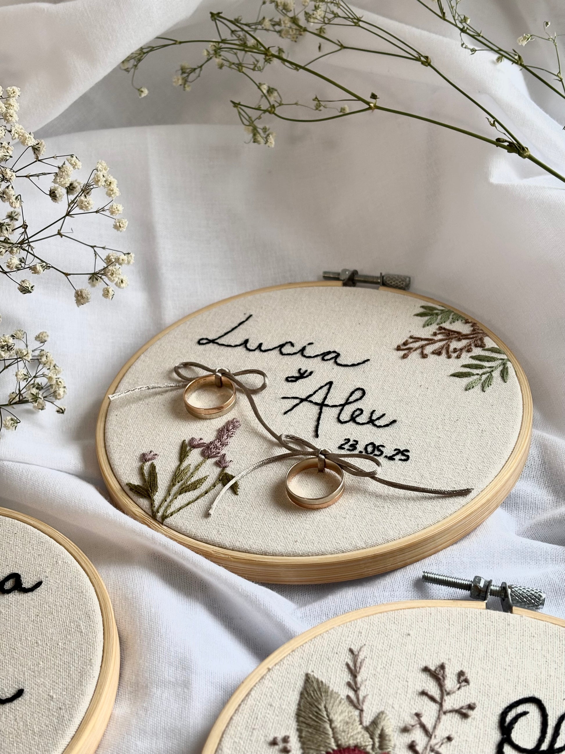 Porta alianzas bordado artesanalmente en bastidor, con flores y lazos, personalizado con nombres para boda única. Hecho a mano en España